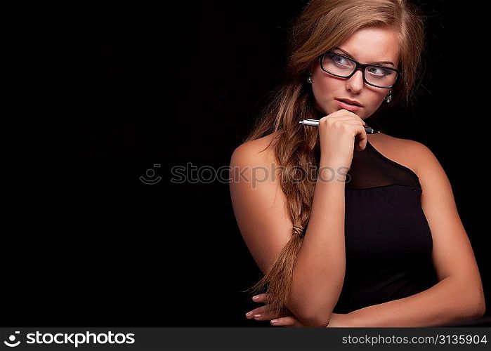 cheerful thinking or planning young business woman with pen, isolated on black background