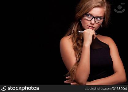 cheerful thinking or planning young business woman with pen, isolated on black background