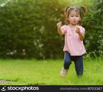 cheerful toddler girl playing grass flower in a field