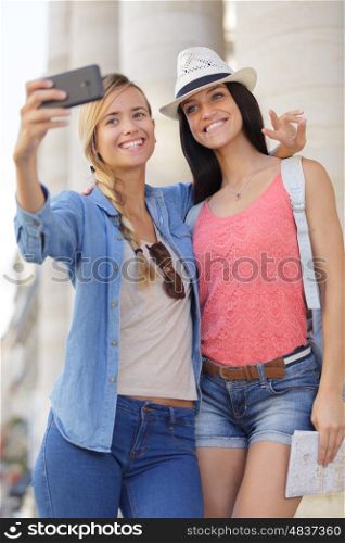 cheerful tourist female friends taking photos of themselves