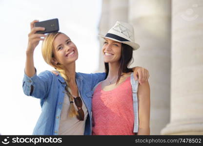 cheerful tourist female friends taking photos of themselves