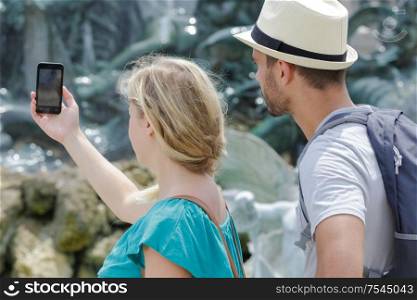 cheerful traveling couple taking pictures with mobile phone