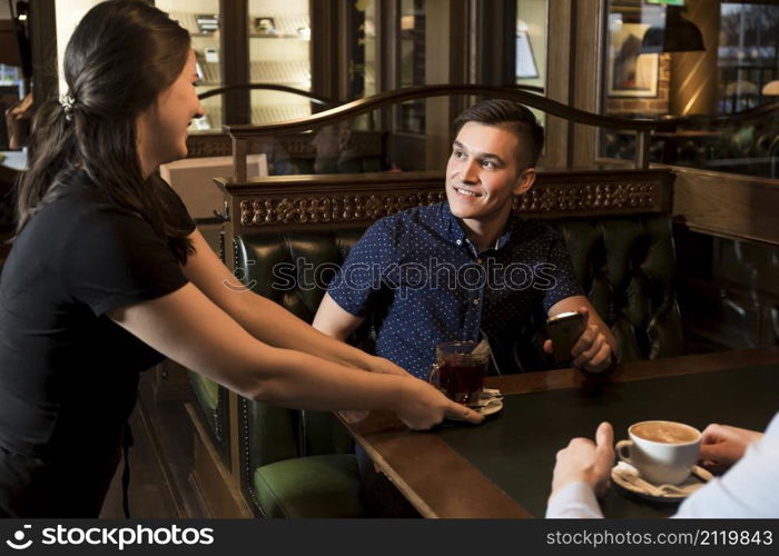 cheerful waitress serving tea handsome man