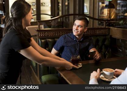 cheerful waitress serving tea handsome man