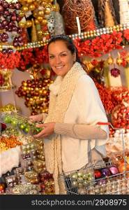 Cheerful woman buyer shopping Christmas ornaments with shopping basket