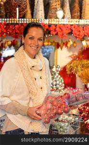 Cheerful woman buying Christmas decoration in plastic boxes