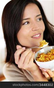 Cheerful woman eating corn flakes for breakfast