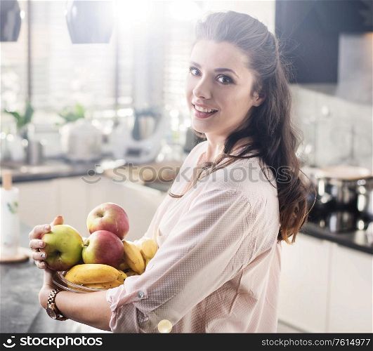 Cheerful woman holding a bowl full of fresh fruit