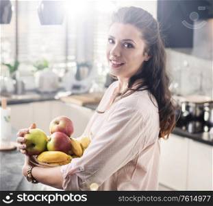 Cheerful woman holding a bowl full of fresh fruit