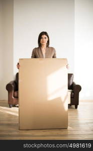 Cheerful woman holding a cardboard box while moving in new home