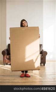 Cheerful woman holding a cardboard box while moving in new home