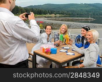 Cheerful woman posing for camera at sidewalk bar with cocktails