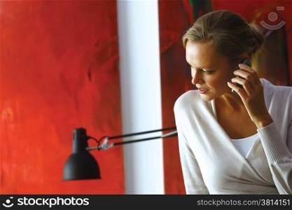 Cheerful woman speaking on mobile phone on living room