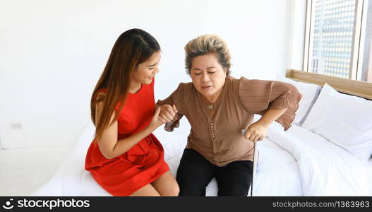 Cheerful woman taking care of her grandmother in bed room at home