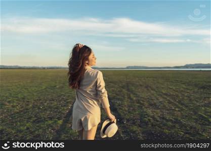 cheerful woman walk across the green field with sunlight
