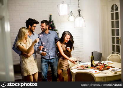 Cheerful women and men celebrating New Year eve with sparkles and wine at home