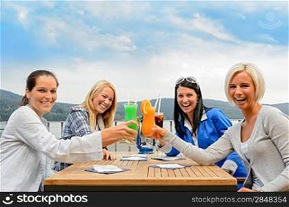 Cheerful women toasting with cocktails at outdoor restaurant summer terrace