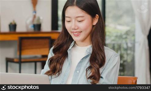 Cheerful Young Asian freelance lady working on laptop at coffee shop. Attractive Japanese businesswoman relax feeling happy in urban cafe or restaurant.
