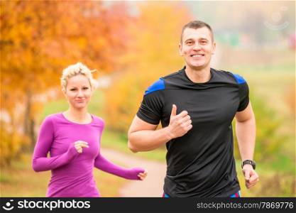 cheerful young athletes jogging autumn morning
