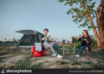 Cheerful Young backpacker couple sitting at front of the tent in forest with coffee set and making fresh coffee grinder while c&ing trip on summer vacation