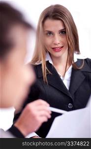 Cheerful young business woman in her meeting with her collegue looking at you over white background