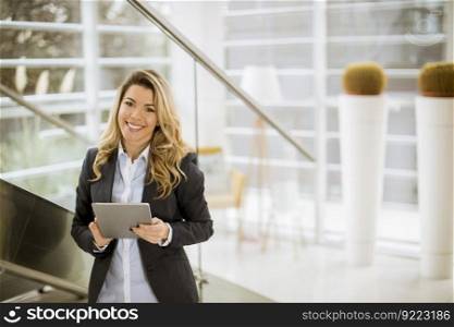 Cheerful young businesswoman with tablet in the modern office