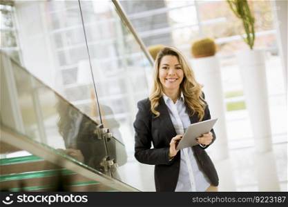 Cheerful young businesswoman with tablet in the modern office