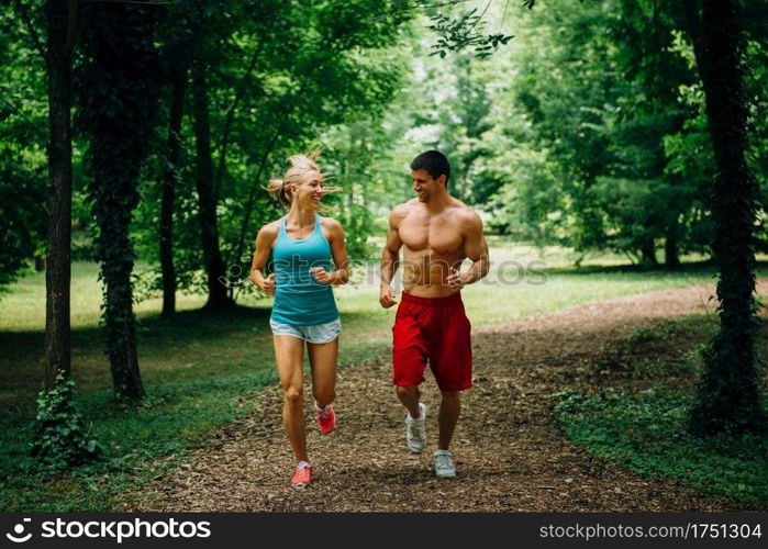 Cheerful young couple jogging in forest