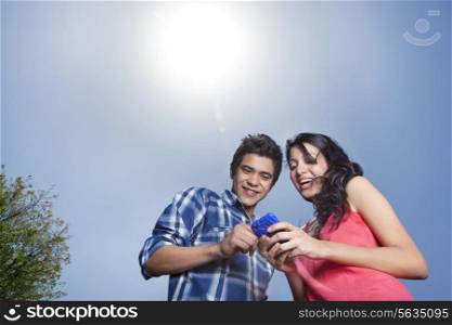 Cheerful young couple looking at mobile phone