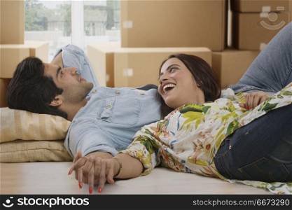 Cheerful young couple lying on floor in living room