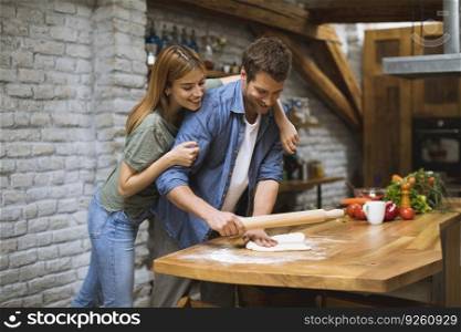 Cheerful young couple making pizza in rustic kitchen together