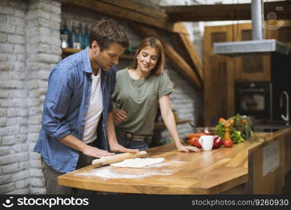 Cheerful young couple making pizza in rustic kitchen together