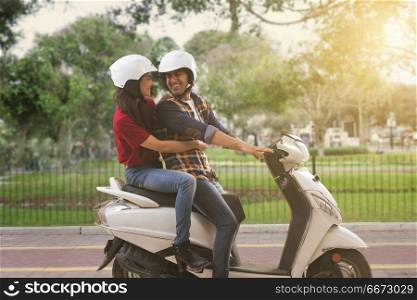 Cheerful young couple riding on a motorbike