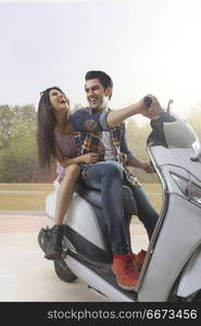 Cheerful young couple riding on a motorbike