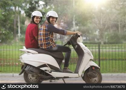 Cheerful young couple riding on a motorbike