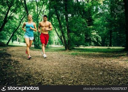 Cheerful young couple running in forest