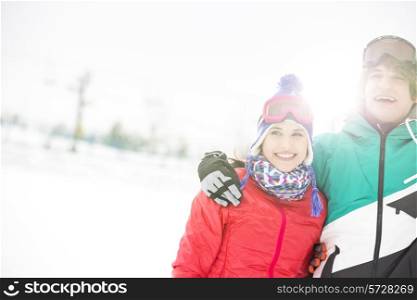 Cheerful young couple standing arm around in snow