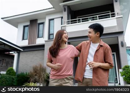cheerful young couple standing outside their house