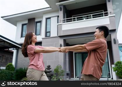 cheerful young couple standing outside their house