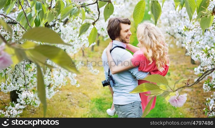 Cheerful young couple walking among apple-trees