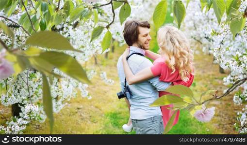 Cheerful young couple walking among apple-trees
