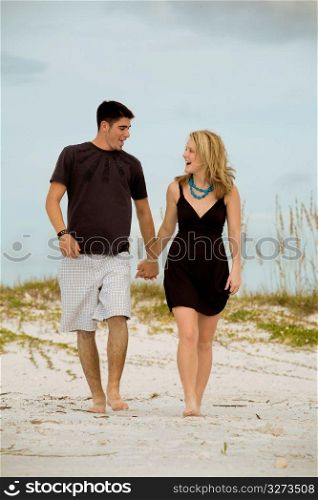 Cheerful young couple walking together on beach