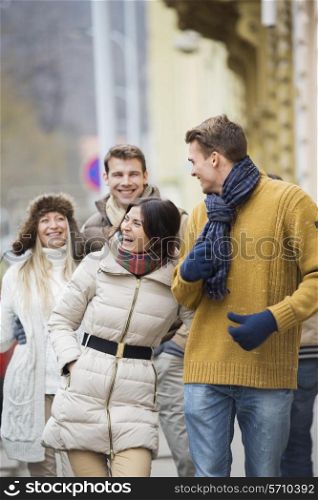 Cheerful young couples in warm clothing on city street