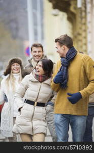 Cheerful young couples in warm clothing on city street