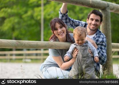 cheerful young family spending time together at the farm