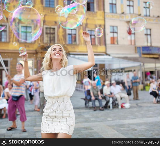 Cheerful young lady catching the soap bubbles