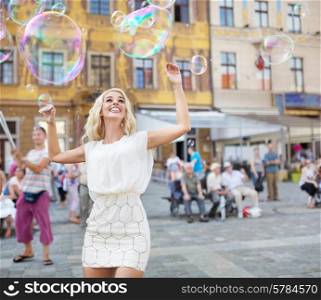 Cheerful young lady catching the soap bubbles