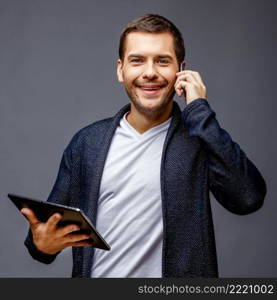 Cheerful young man in smart casual wear against grey background. Cheerful young man in smart casual wear