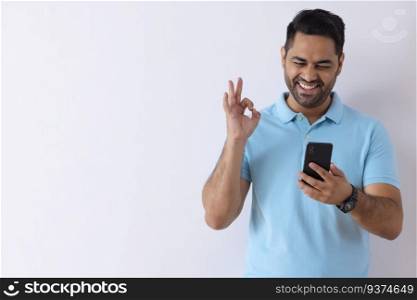 Cheerful young man showing Ok hand gesture while talking to video call on Smartphone