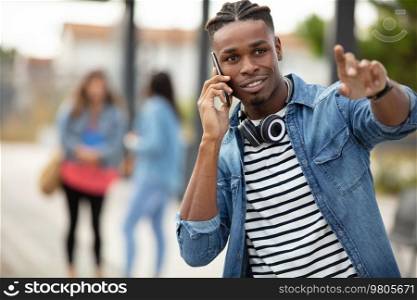 cheerful young man talking on phone and showing way